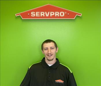 male employee smiling in front of green background