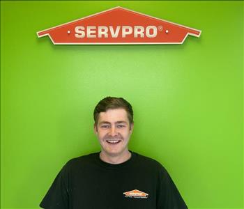 male employee smiling in front of green background