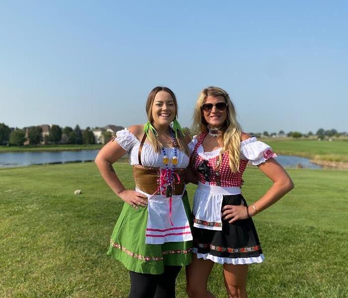 two females standing on golf course in german dresses