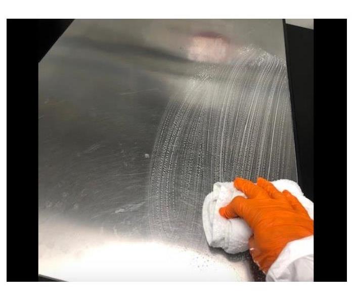 technician wearing orange glove wiping down table 