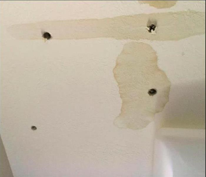 brown water stains and holes in ceiling
