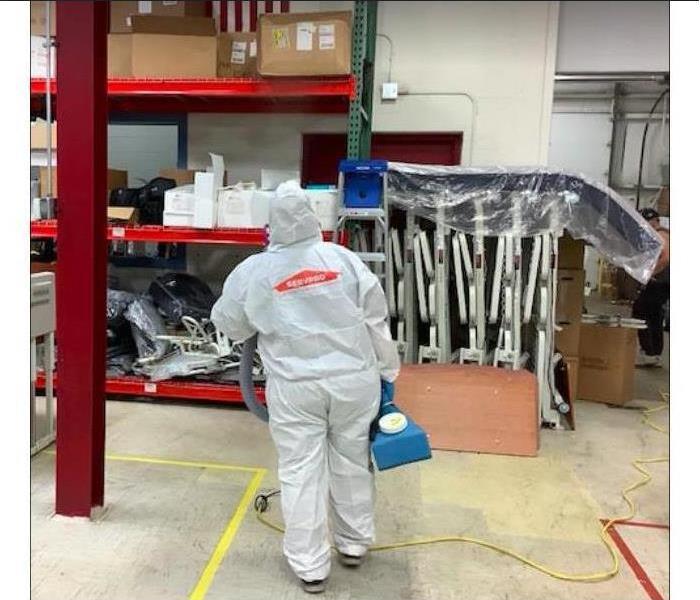 servpro employee in hazmat suit spraying 